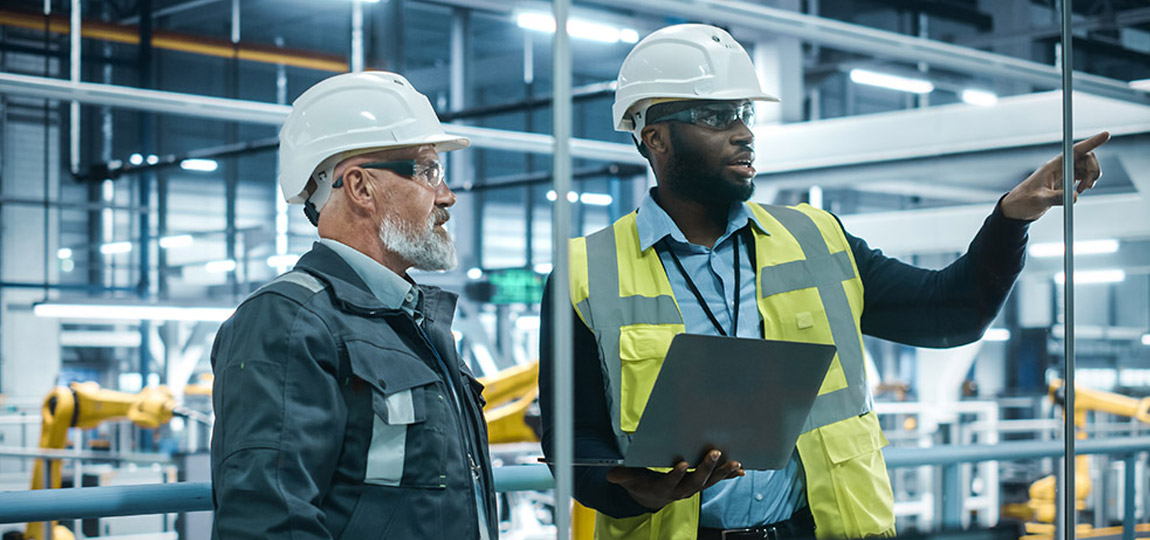Two men in a manufacturing plant using a tablet equipped with AI analytics software for decision making and accurate planning