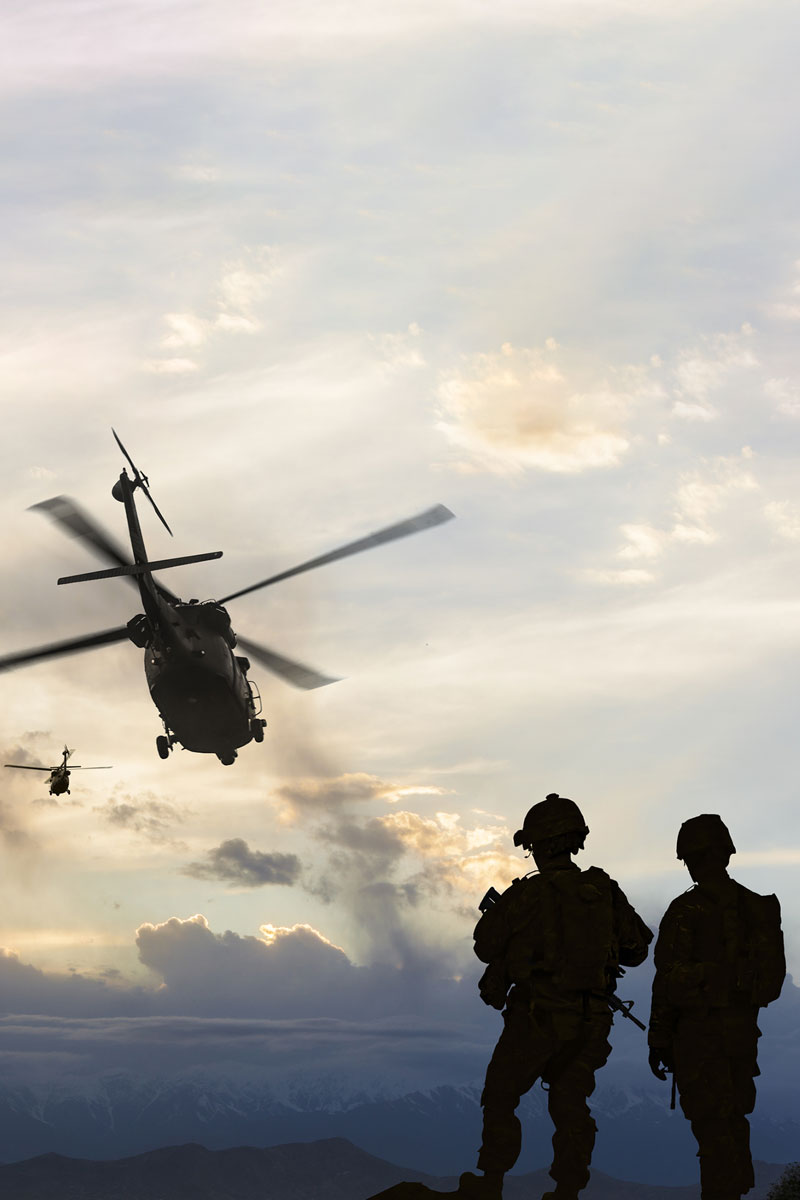 2 soldiers and helicopters in silhouette